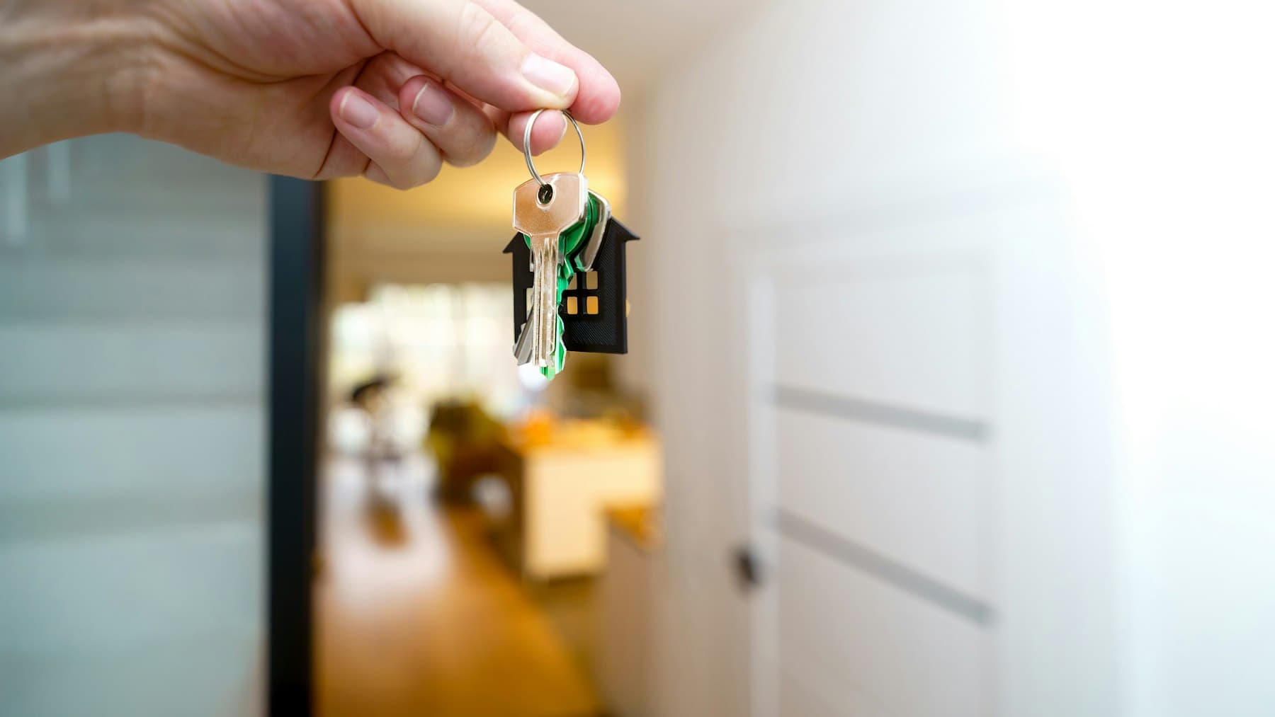 House keys held at the entrance of a property, representing access and owner handover.
